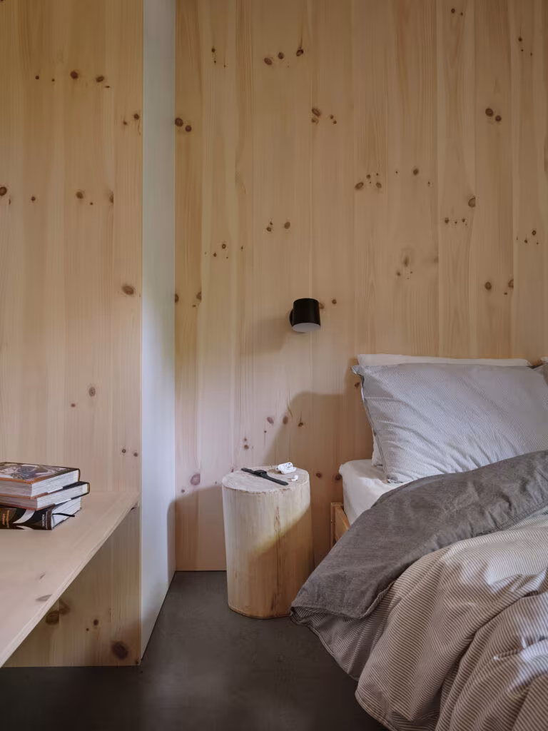 Bedroom with a knotty pine wall, log bedside table, built-in desk and dark floor, TISSARAOUATA
