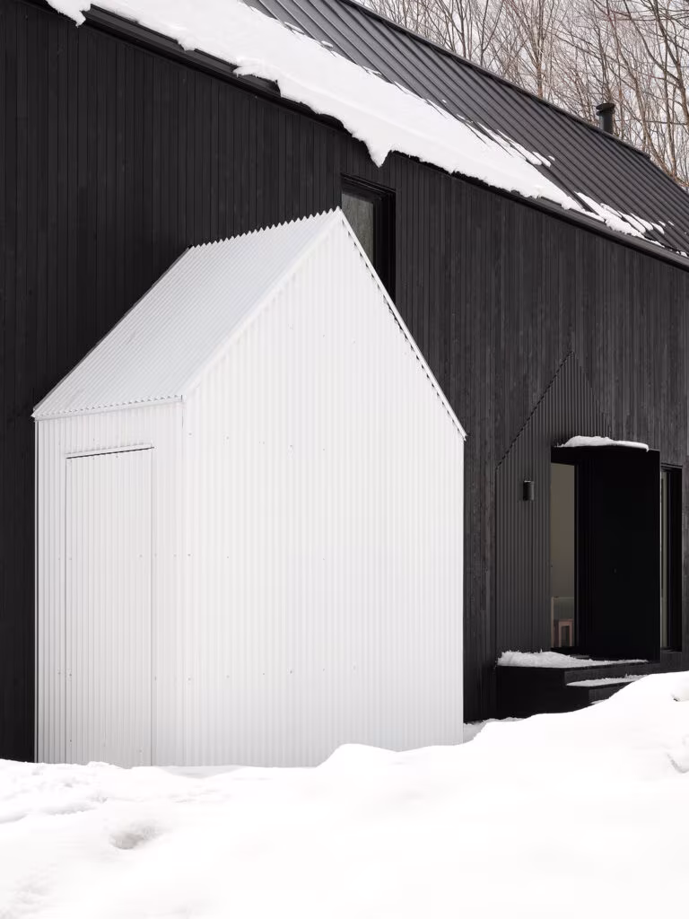 Black timber house with a white annex dressed in snow, TISSARAOUATA