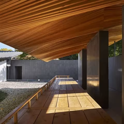 Plataforma de tablas de madera junto a un pilar oscuro bajo la cubierta inclinada de Ueno Toshogu