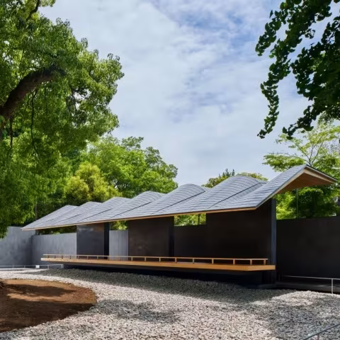 Pabellón de Hiroshi Nakamura & NAP en Ueno Toshogu, con cubierta quebrada y plataforma de madera sobre la grava