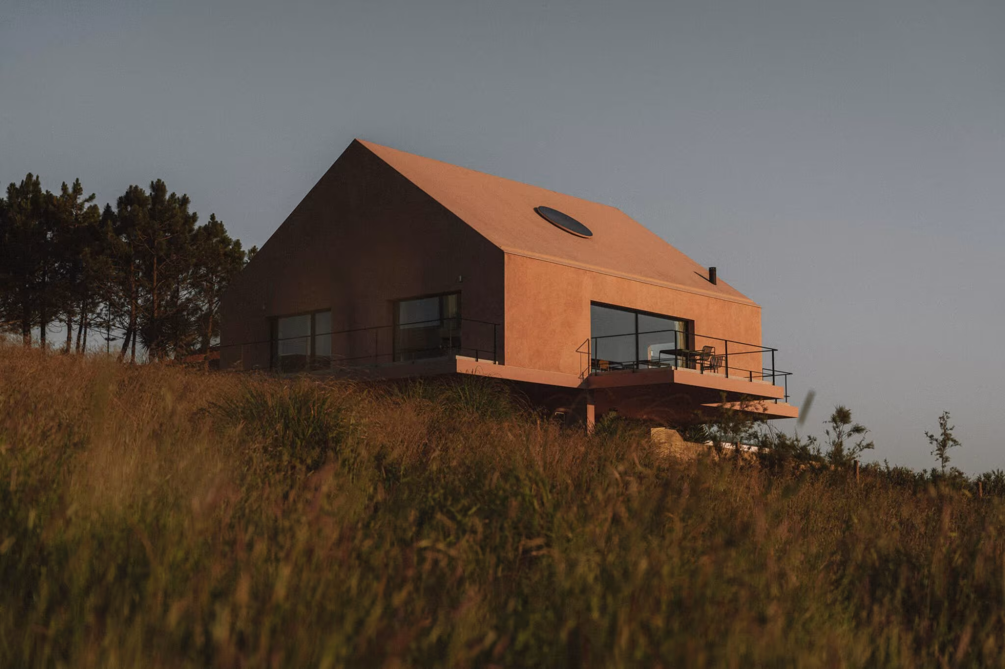 Casa Plaj on the hillside at dusk with a cantilevered terrace and sea views