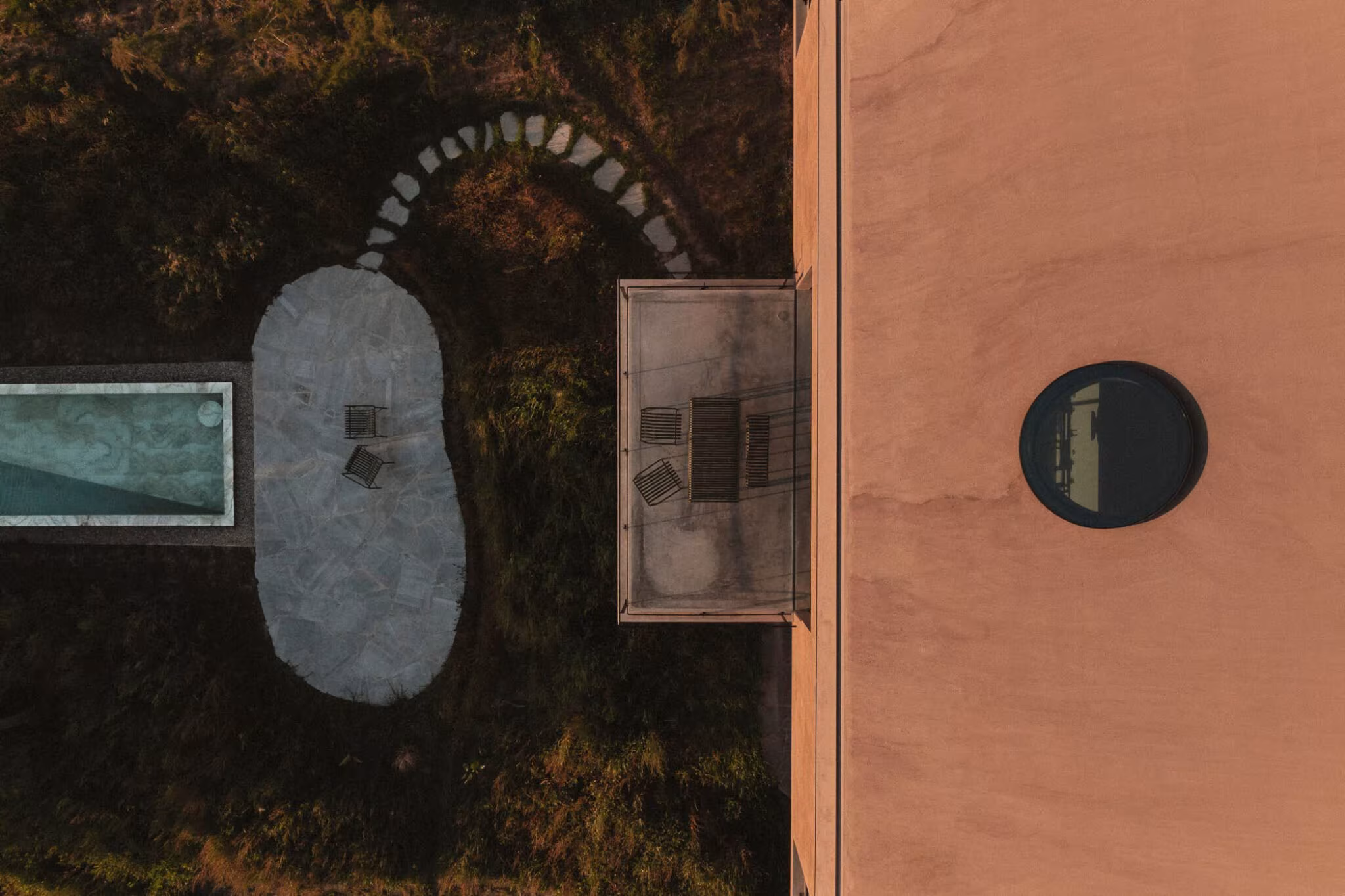Aerial view of the garden of Casa Plaj with a stone water basin beside the red wall and its round window
