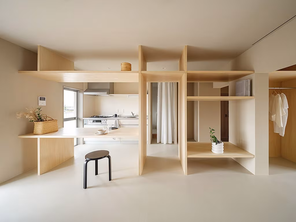 Estancia de contrachapado claro con estantería abierta y cocina al fondo en Omoya y Hanare de YSLA Architects, Osaka