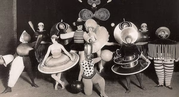 Geometric costumes of Oskar Schlemmer's Triadic Ballet against a black background at the Bauhaus