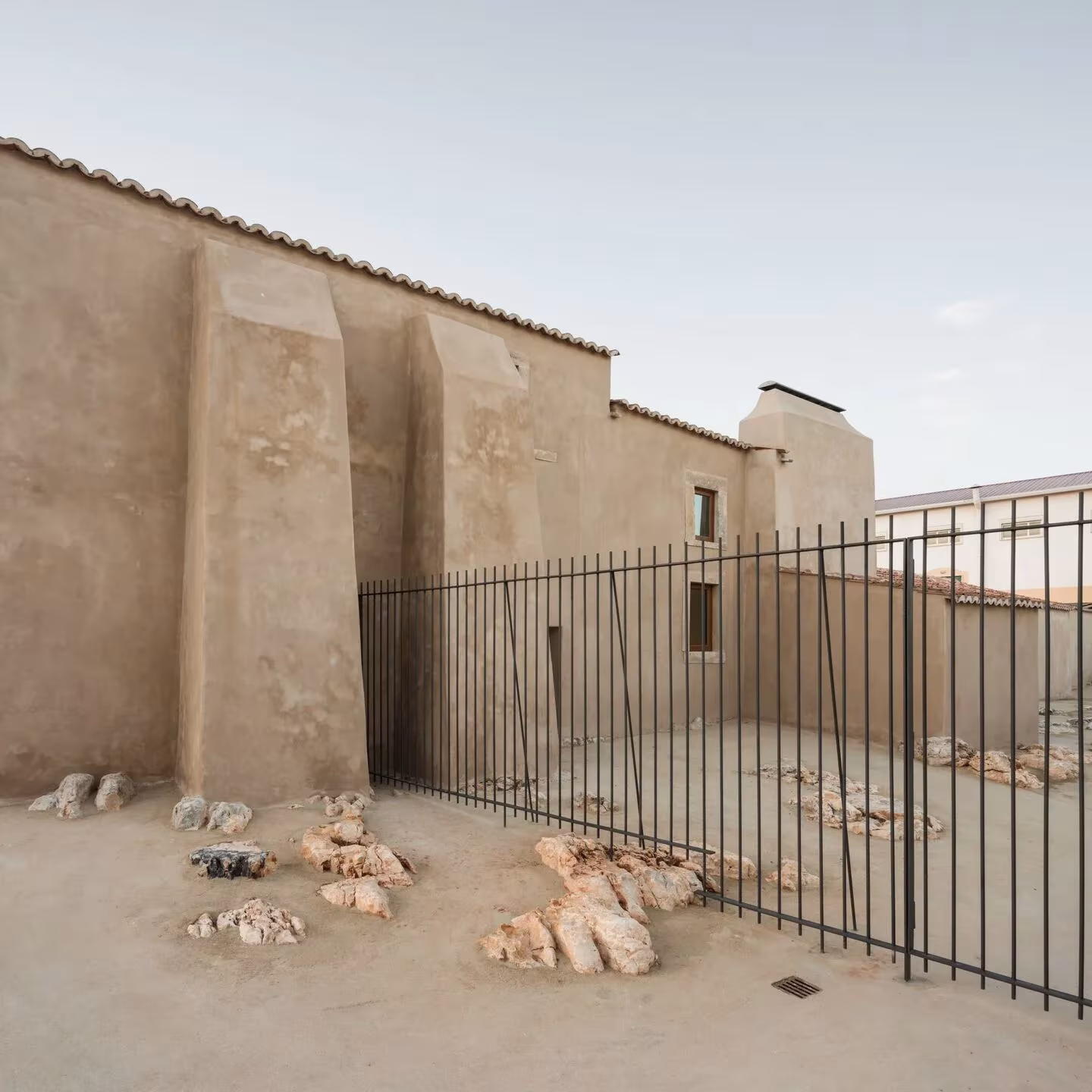 Muro de la casa rural original con reja metálica y piedras en el patio del Casal Saloio