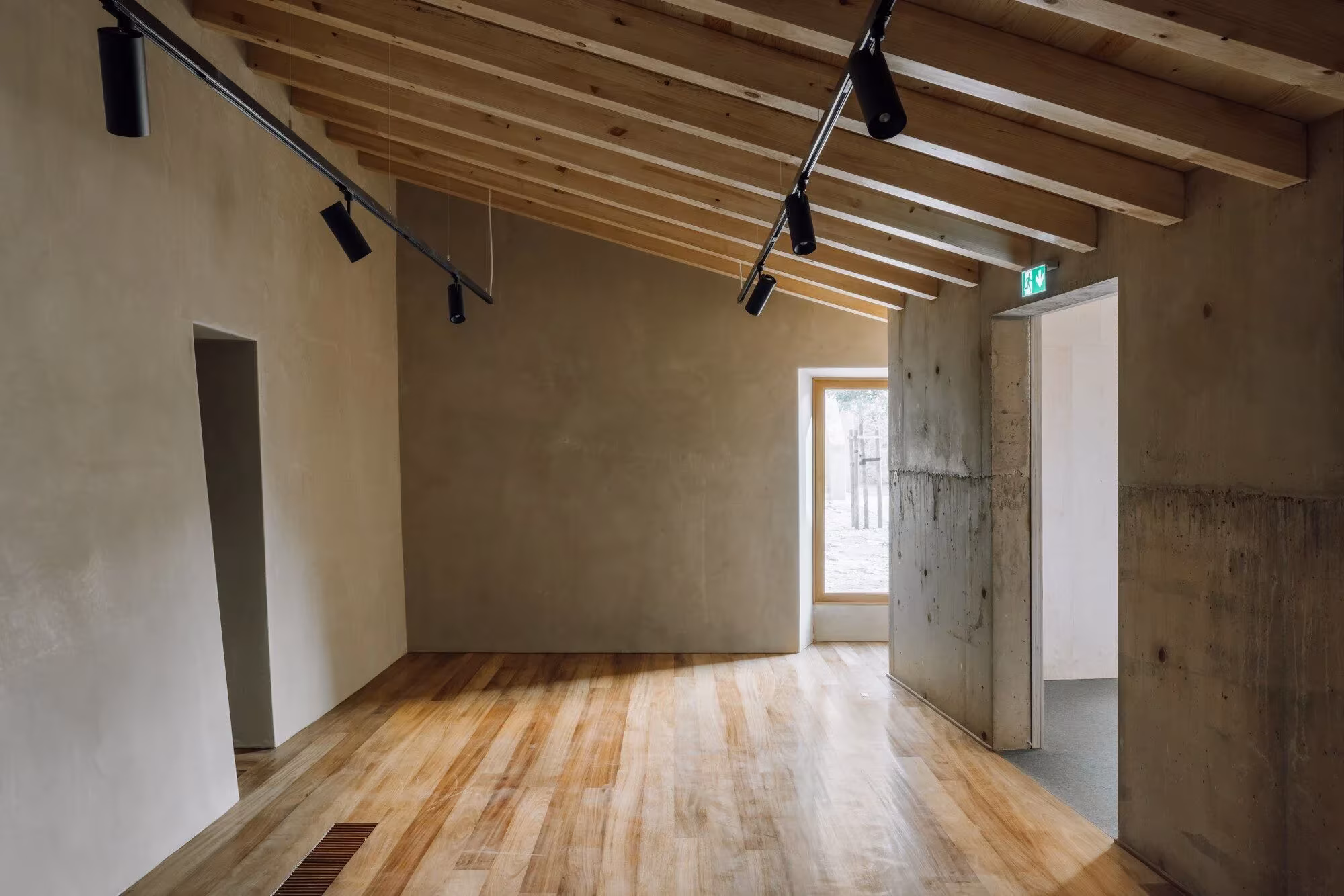 Sala del Casal Saloio con techo de vigas de madera, focos sobre carril y suelo de tarima
