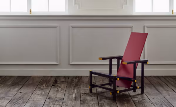 Rietveld Red and Blue chair in a room with panelled walls and a weathered timber floor