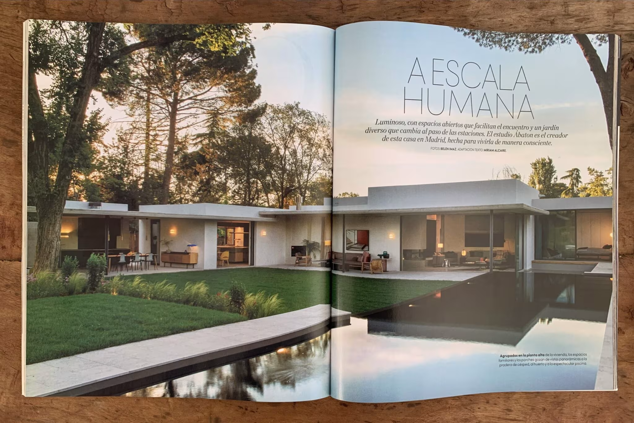 Revista abierta con el titular A escala humana y una casa baja de ÁBATON reflejada en el agua al atardecer