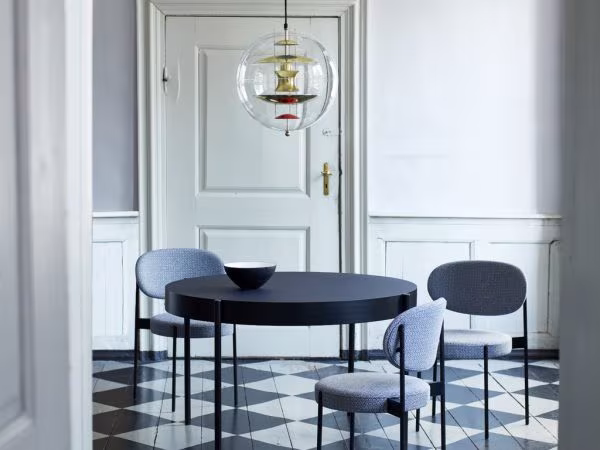 Verner Panton Globe lamp over a black table with blue upholstered chairs and a chequered floor