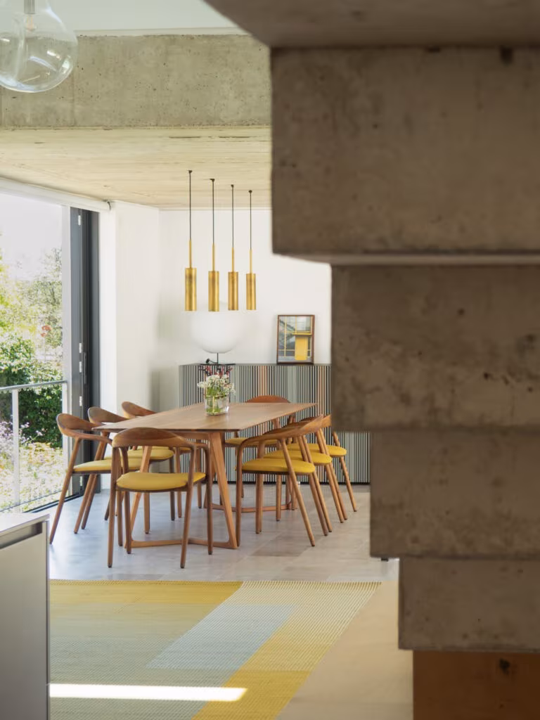 OLYMPUS DIGITAL CAMERA Dining area behind a stacked-block concrete pier with golden pendants and a yellow rug in Casa de las encinas