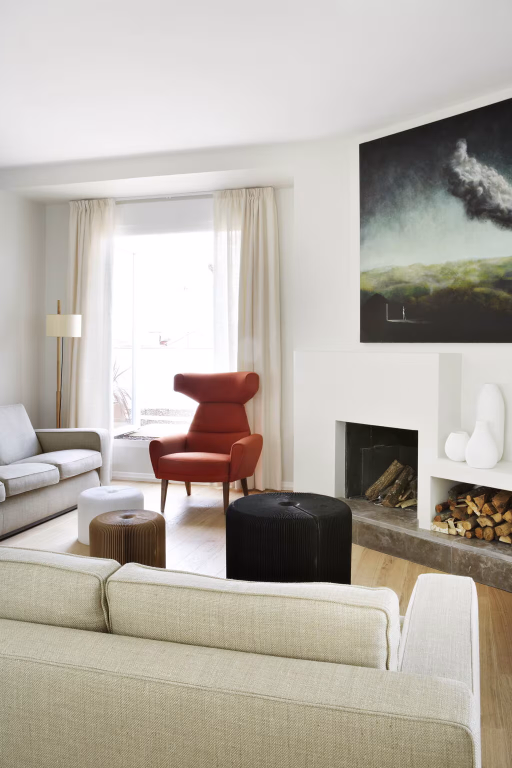 Living room with sofas, red armchair, fireplace and painting in the Rosales refurbishment by Ábaton, Madrid
