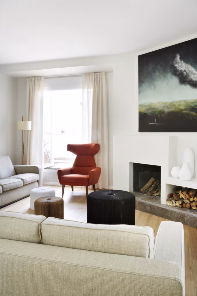Living room with sofas, red armchair, fireplace and painting in the Rosales refurbishment by Ábaton, Madrid