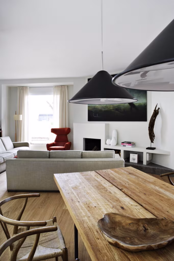 Timber table with black conical pendant and living room beyond in the refurbished old house in Rosales, Madrid