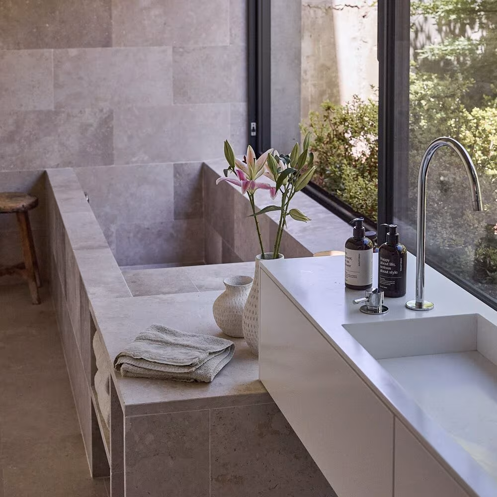 Abaton Montegancedo_38_WEB Stone-clad bathroom with built-in bath, long basin and a large window over the garden in Casa de las encinas