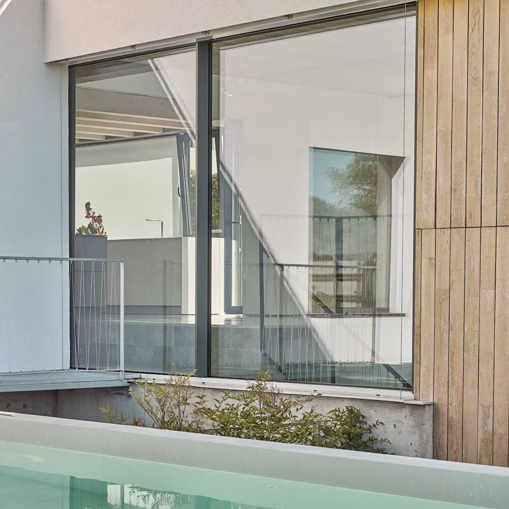 Abaton Montegancedo_57_WEB-2 Glazed facade with timber slats and a glass balustrade above the pool water in Project PC