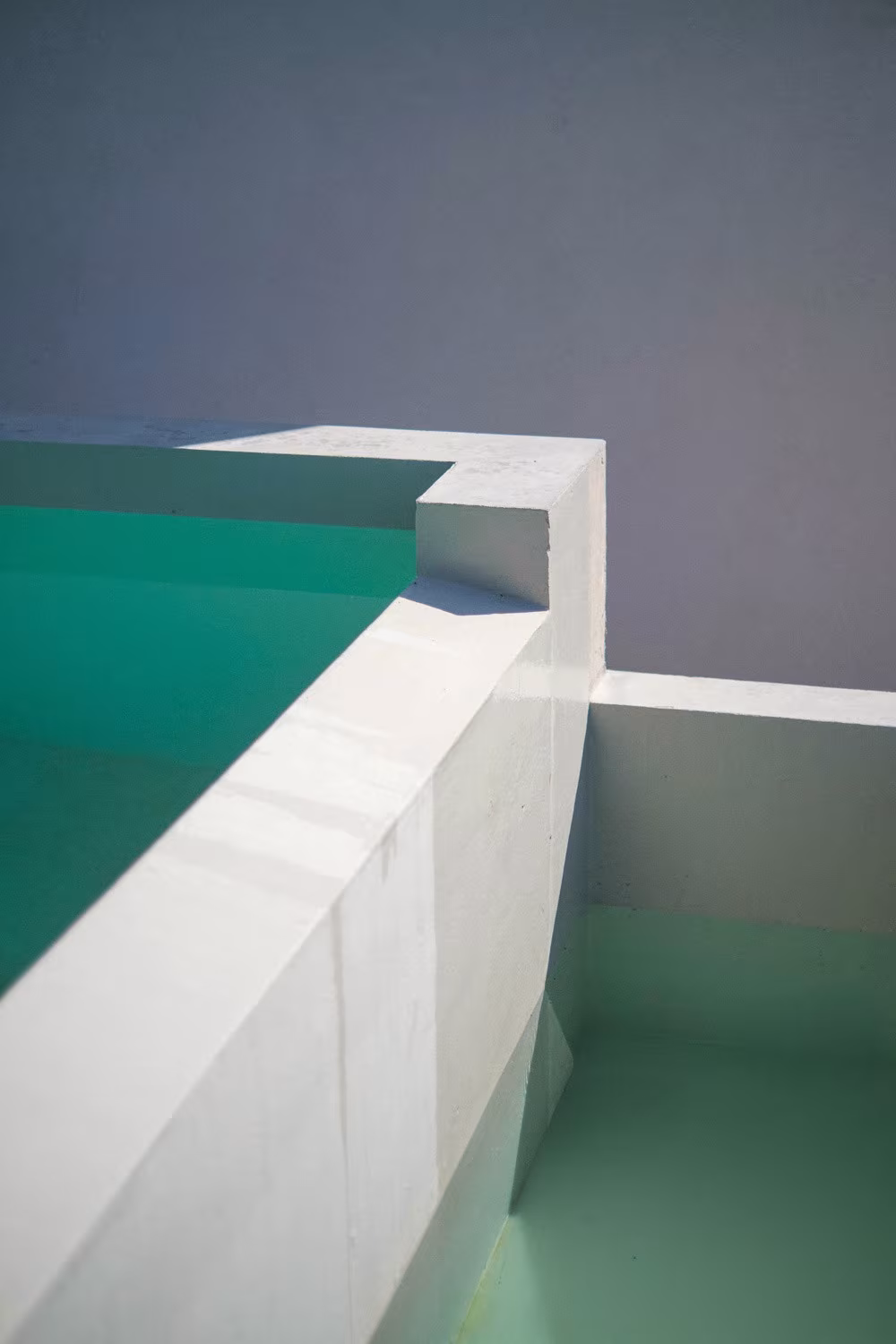 Abaton – Pozuelo 1 Detail of the pool's concrete edge with turquoise water and a stepped weir in Casa de las encinas