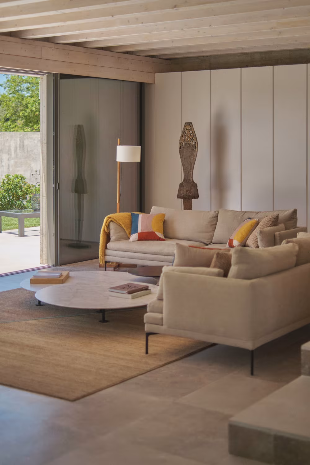 Abaton – Pozuelo 126 L-shaped sofa, round low table and timber sculpture on a natural-fibre rug in Casa de las encinas
