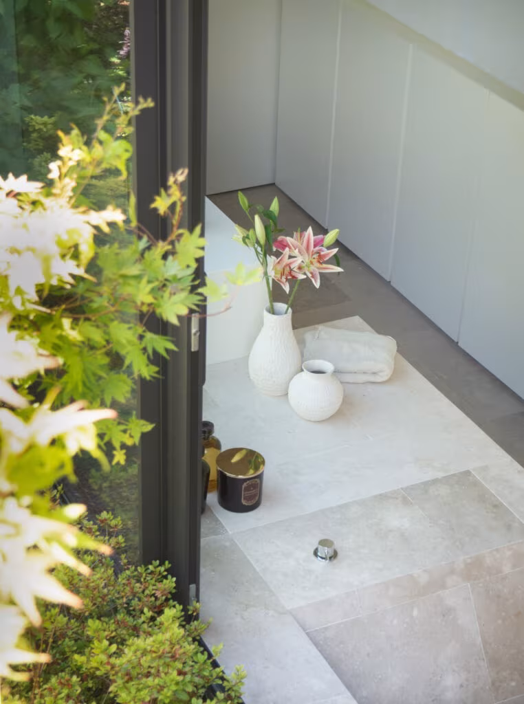 OLYMPUS DIGITAL CAMERA Pale stone bath with vases and flowers beside glazing with maples in Casa de las encinas