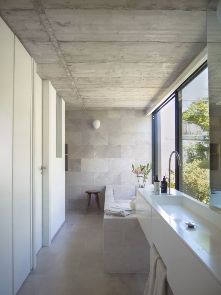 OLYMPUS DIGITAL CAMERA Elongated bathroom with concrete ceiling, long white basin and a window running along the stone wall in Project PC