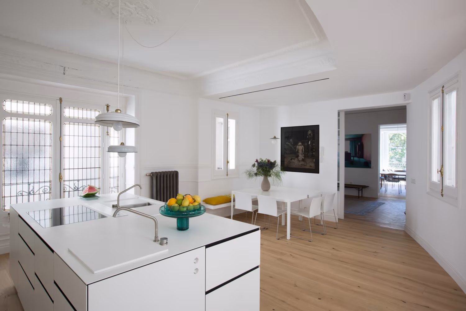 ABATON-reforma-integral-en-sagasta-19 Kitchen with white island and dining area beyond under a moulded ceiling in the Sagasta refurbishment