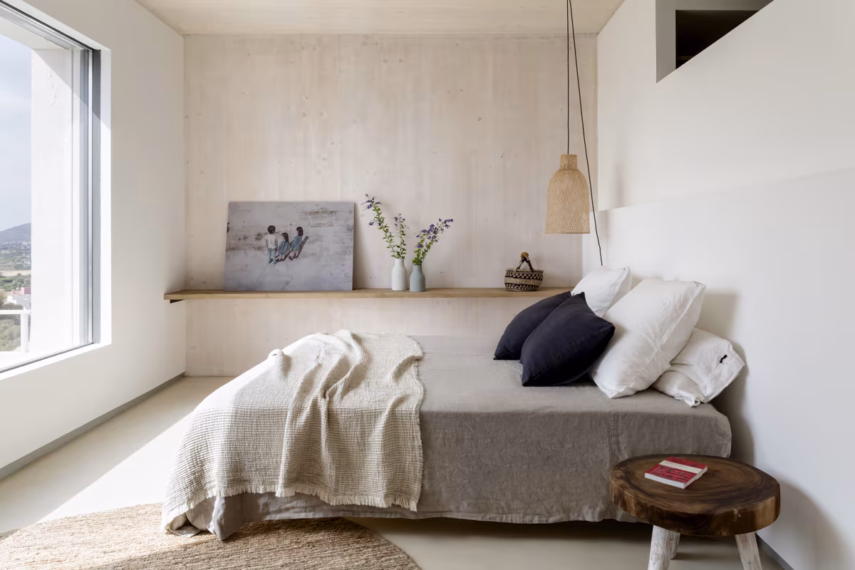 Dormitorio de paredes de madera clara con ventana, cama vestida de lino y balda corrida en Birdhide
