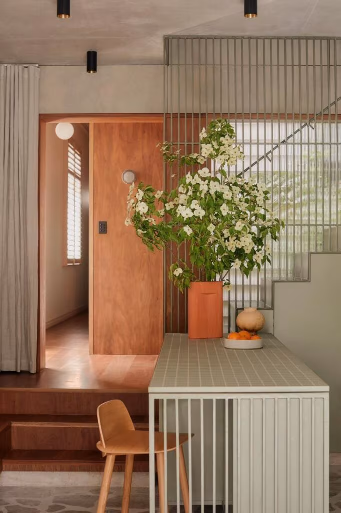 Cocina con isla de azulejo claro, puerta de madera, celosía y silla de roble en una casa de estilo escandinavo