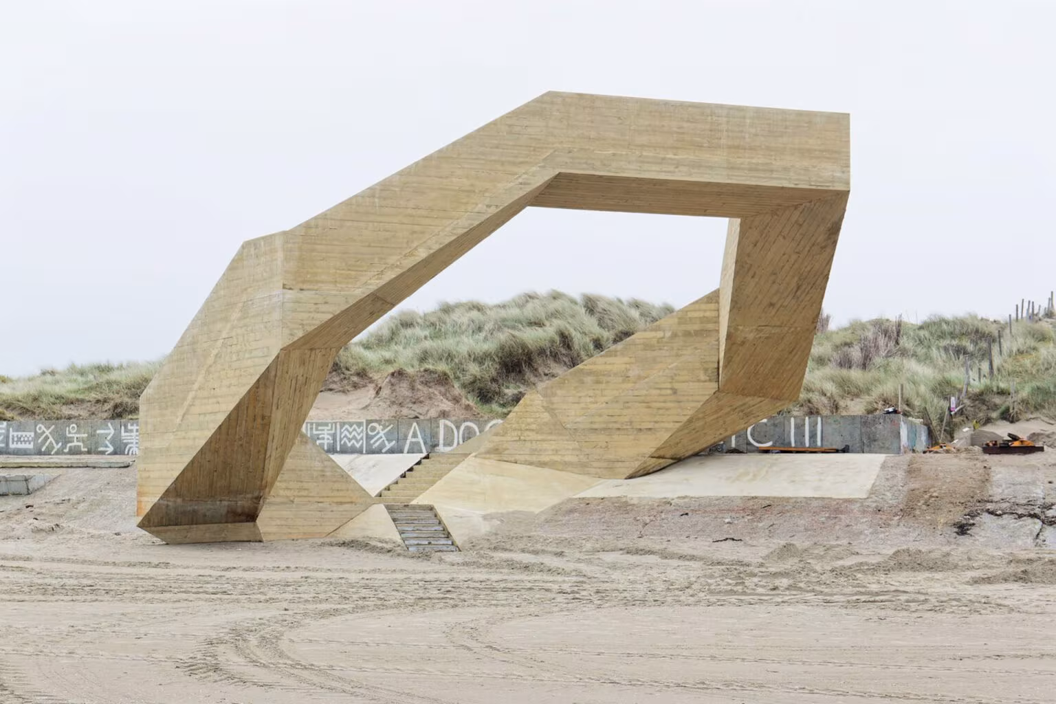 Estructura poligonal de hormigón de Westerpunt entre dunas y paseo, vista en perspectiva baja