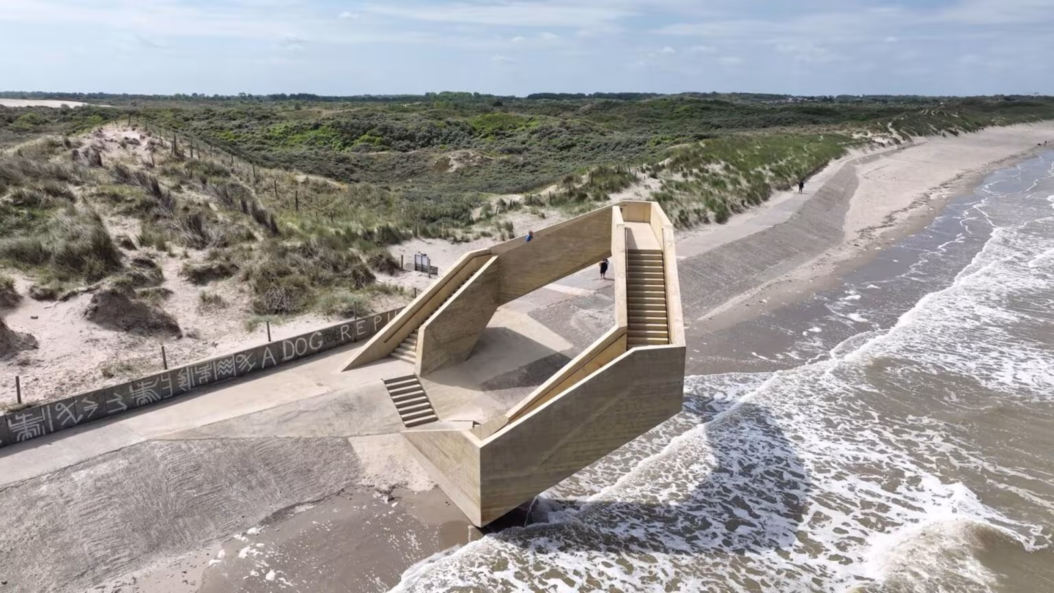 Vista aérea de la escalera-mirador de Westerpunt con las olas rompiendo junto al dique en De Panne