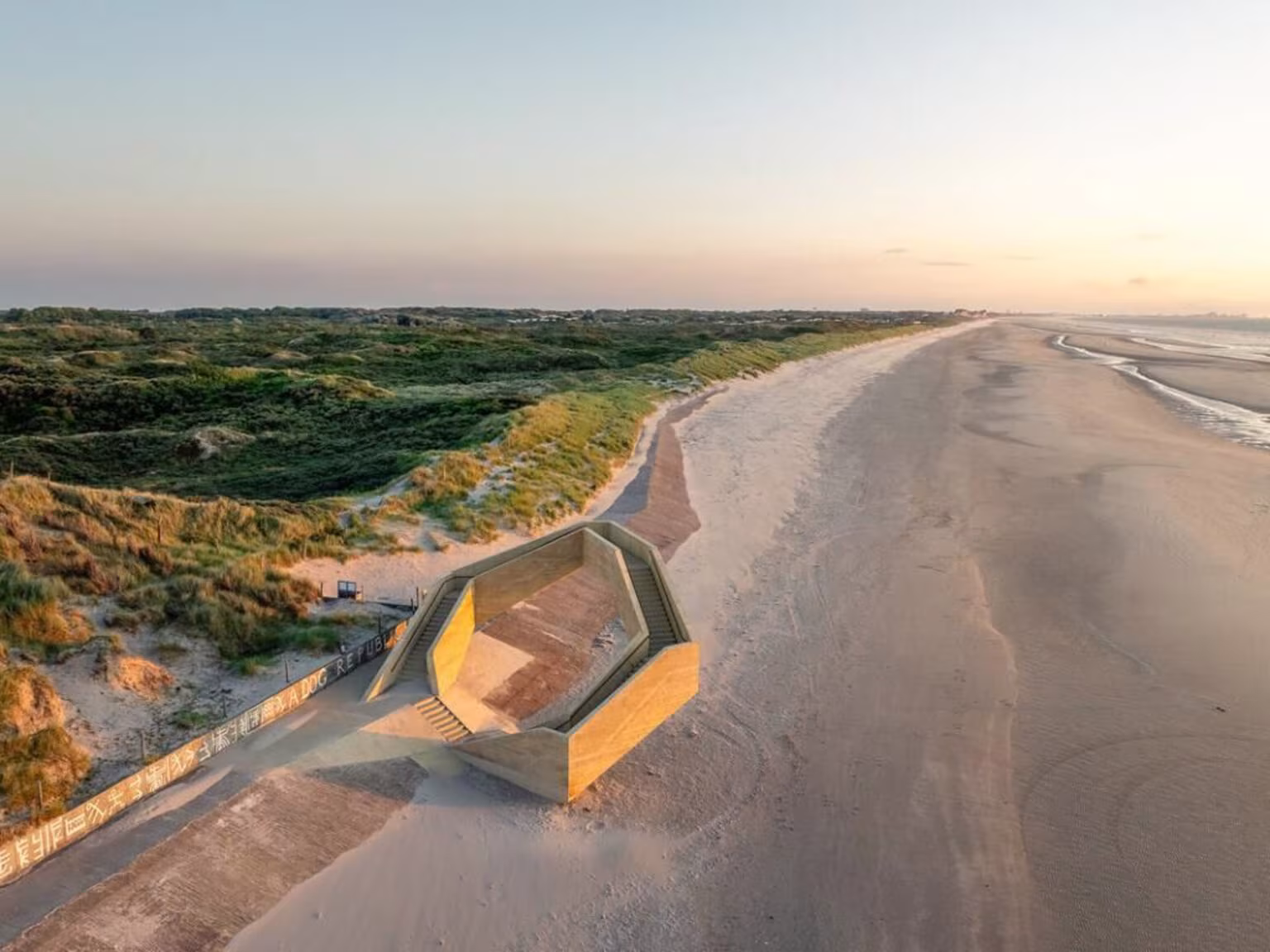 Vista aérea de Westerpunt sobre el paseo marítimo vacío junto a las dunas al amanecer