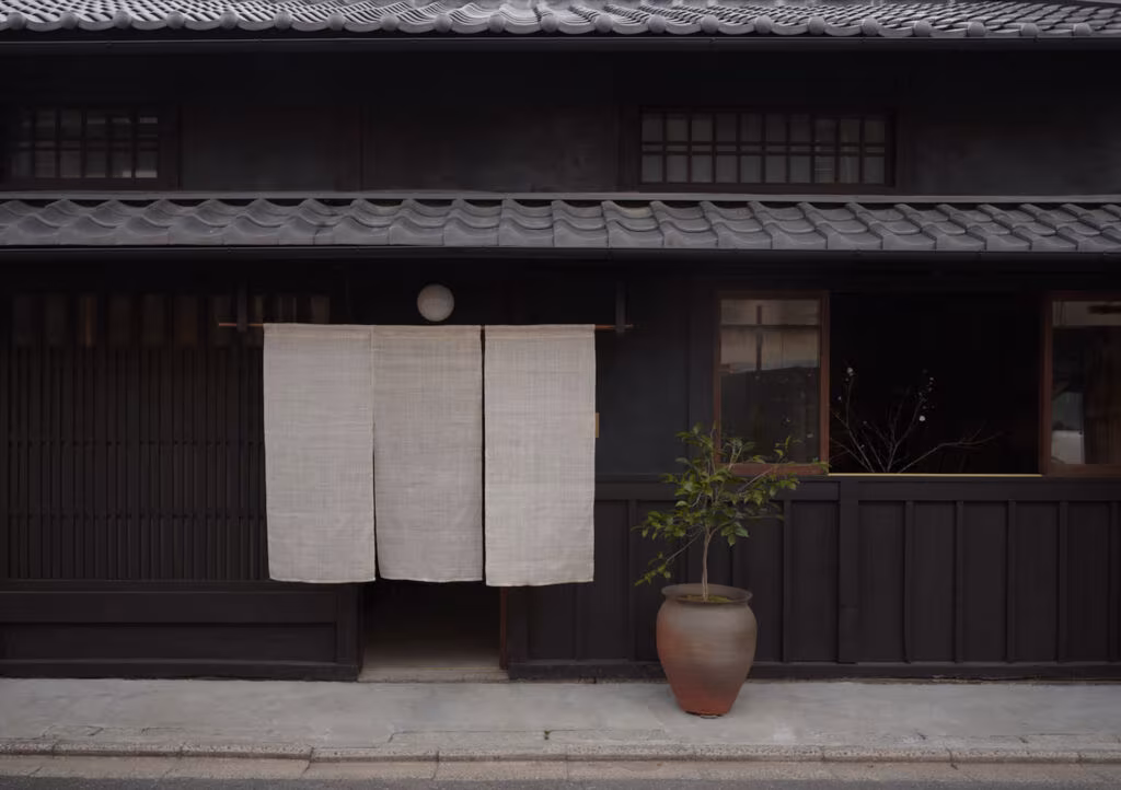 Fachada de madera oscura y tejado de teja del Maana Atelier de Sahena Design en el barrio de Nishijin, Kioto