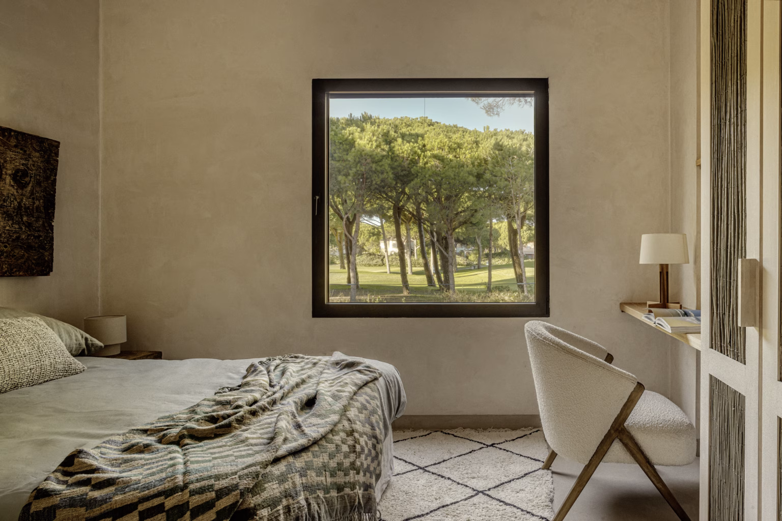 Dormitorio con ventana cuadrada de marco negro hacia los pinos y escritorio junto a la cama en Villa Arena