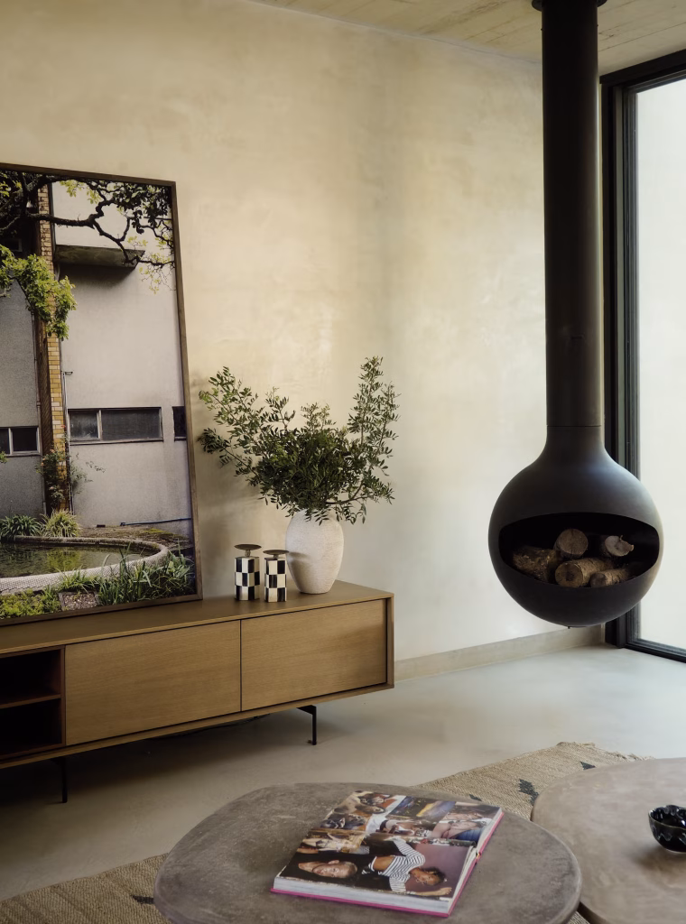 Chimenea negra suspendida junto a un aparador de roble en el salón de Villa Arena de ÁBATON