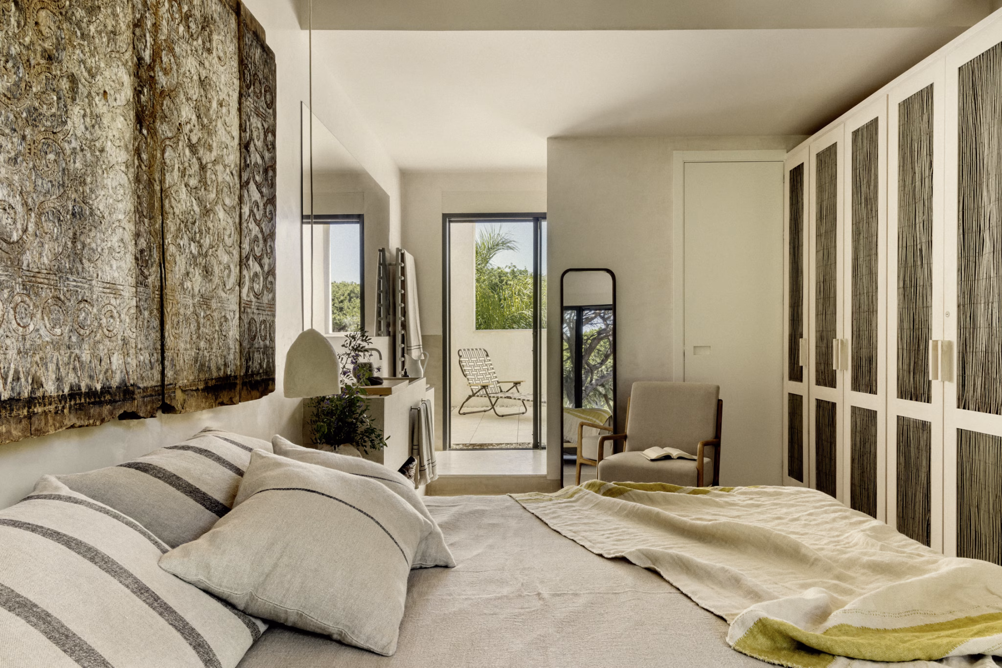 Dormitorio con panel de caña trenzada sobre la cama, armarios de lamas y ventana al jardín en Villa Arena
