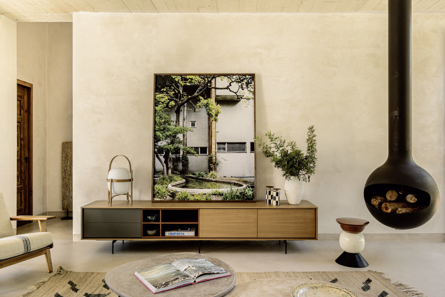 Mueble bajo con espejo y chimenea negra suspendida sobre pavimento continuo en el salón de Villa Arena