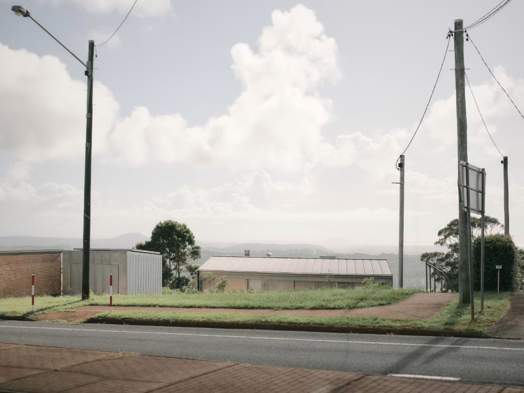 Casa de Atelier Chen Hung en lo alto de la ladera vista desde la carretera con postes de luz en Blackall Range