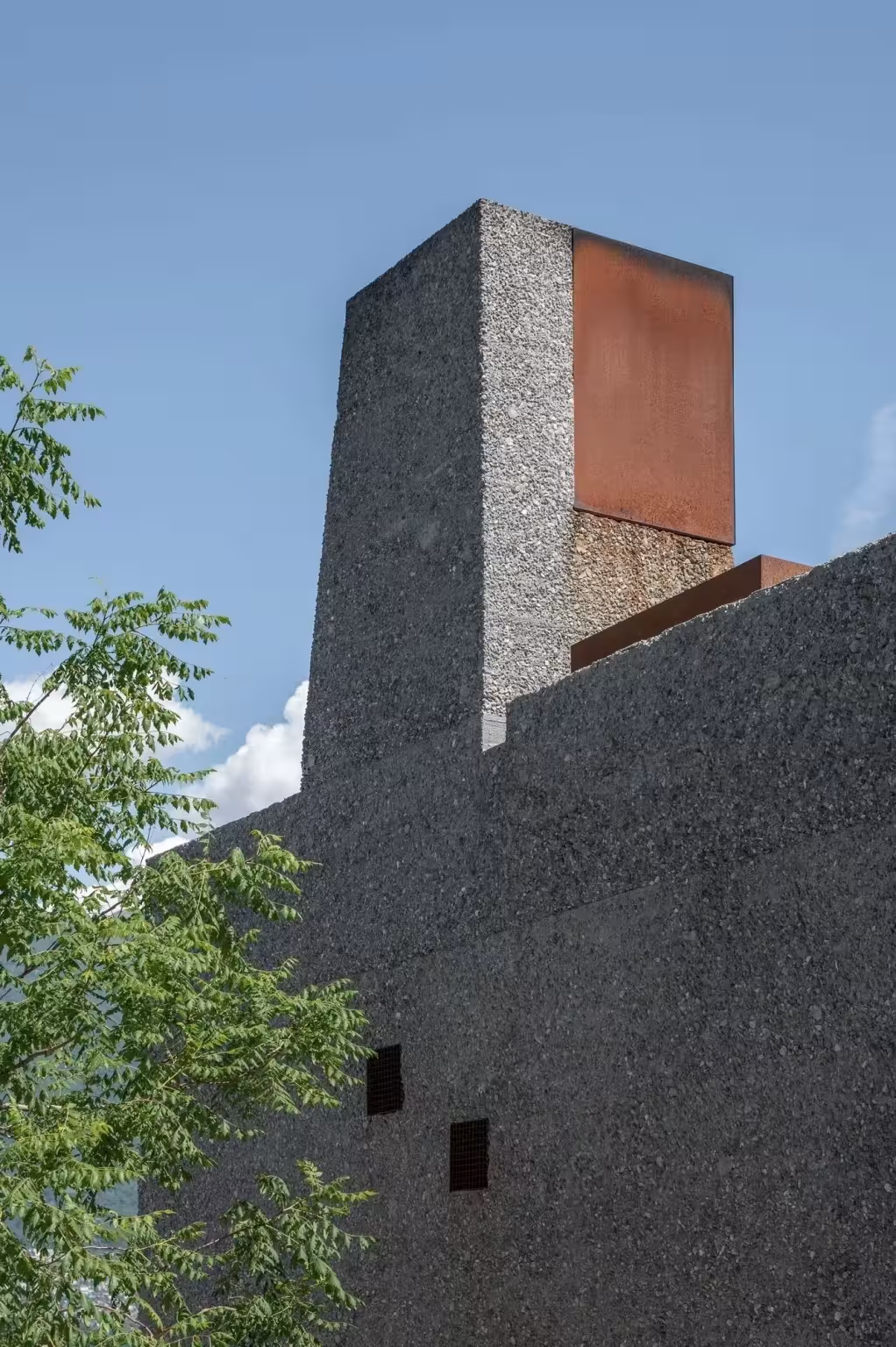 Chimenea de piedra rematada con una pieza de acero corten sobre el volumen de San Nazzaro, Wespi de Meuron Romeo