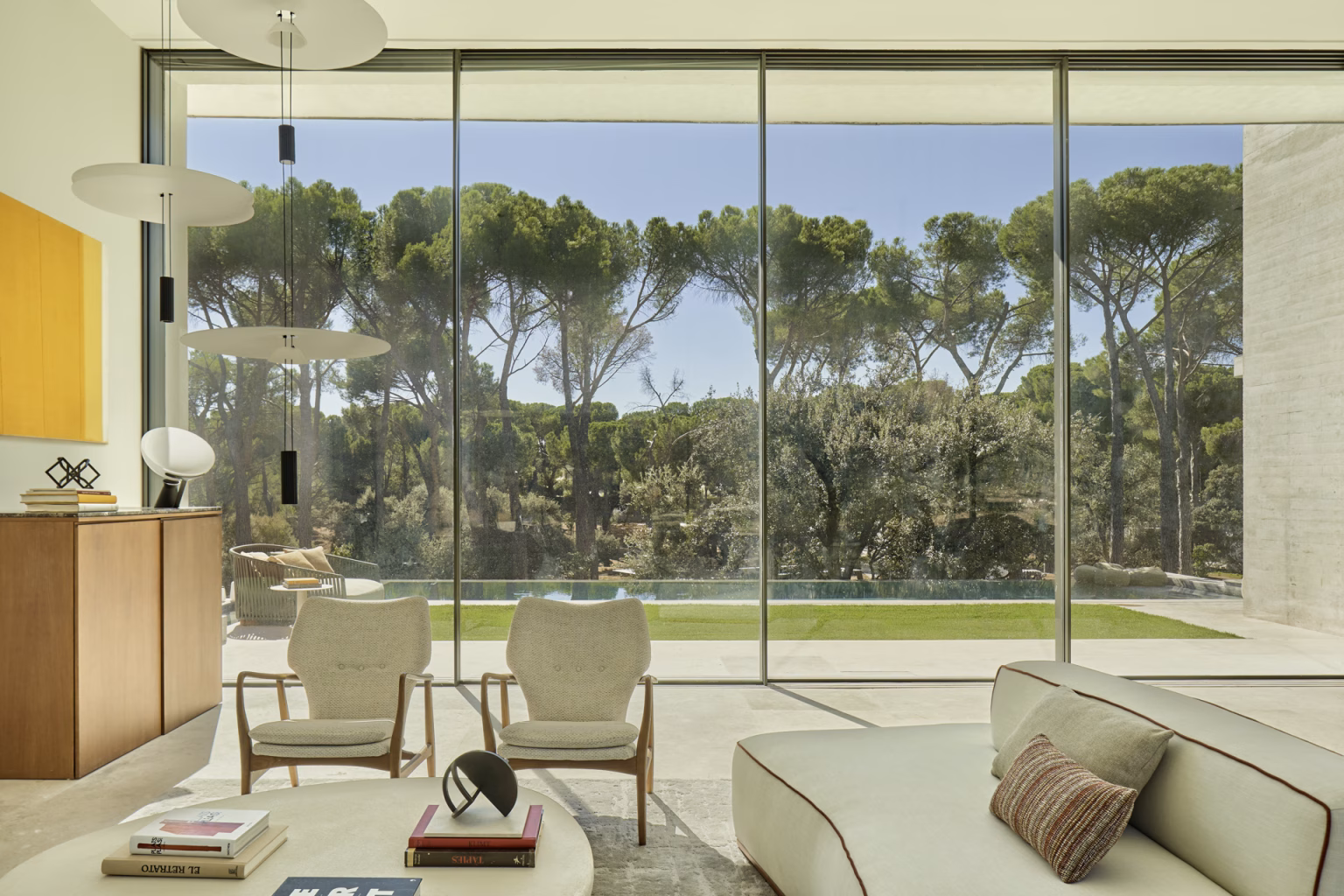 Escorzonera living room opening through continuous glazing to pines and lawn