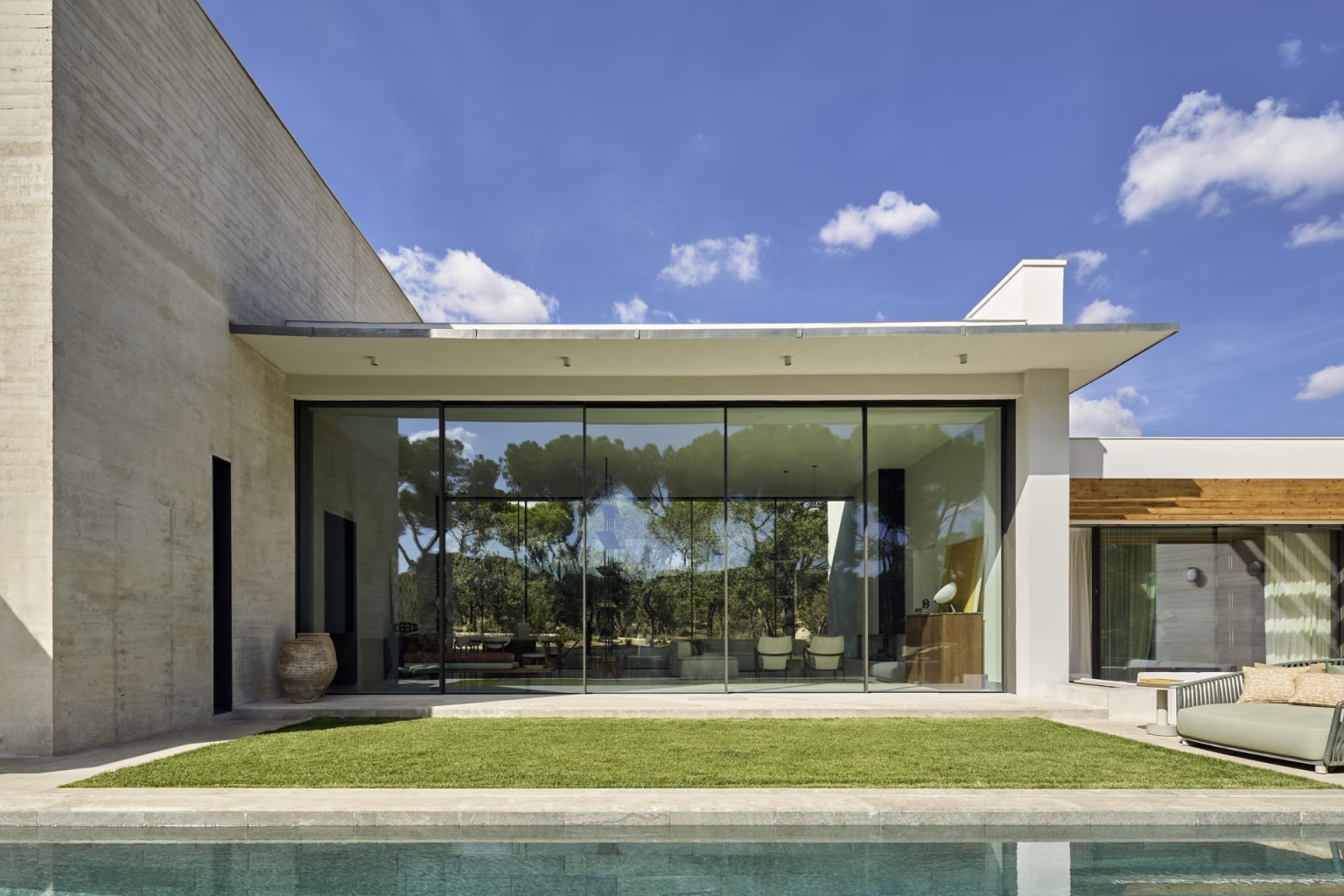 Escorzonera house facade with a large glazed wall over the lawn and pool under a cantilevered flat roof