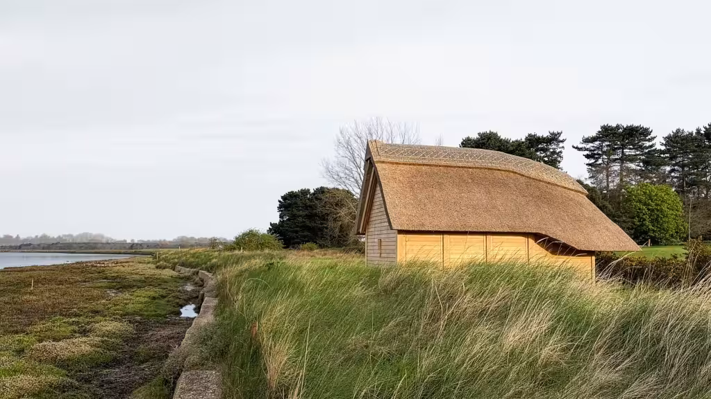 Alde Boathouse de Richard Parr Associates, cobertizo con cubierta de junco entre la marisma y el río