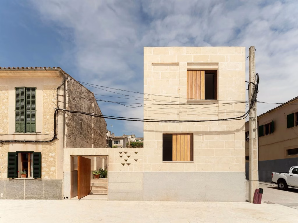 Can Guillem i na Cati by TEd'A arquitectes in Montuïri, a limestone volume with timber shutters beside neighbouring houses
