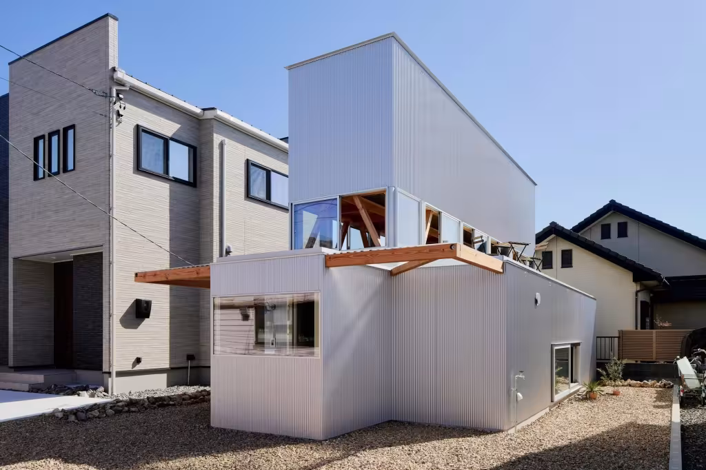 House TN de 1-1 Architects en Anjo, dos volúmenes de chapa blanca apilados entre casas vecinas